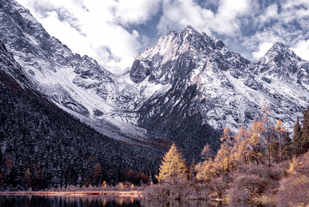 photography of snow-capped mountain beside body of water during daytime