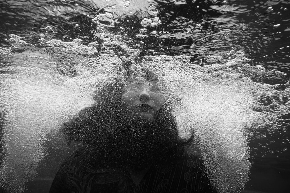 Foto en escala de grises de una persona bajo el agua