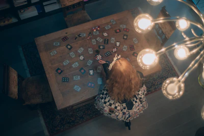 A woman in elegant attire channeling energy with tarot cards under warm lighting.