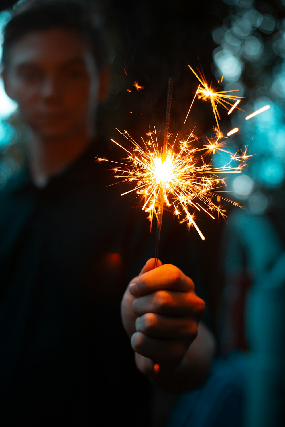 bokeh photography of man holding lighted sparkler