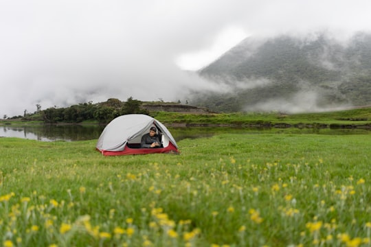 person inside white and red tent across foggy mountain in Benguet Philippines