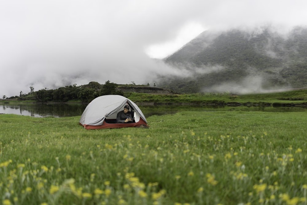 person inside white and red tent across foggy mountain