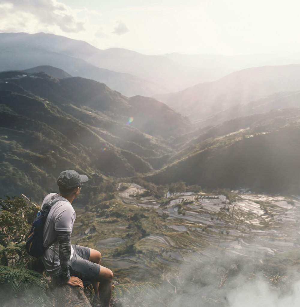 man sitting on top of mountain during daytime