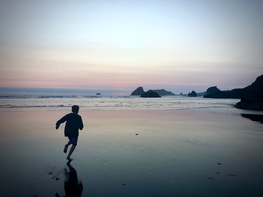 a person running on a beach near the ocean