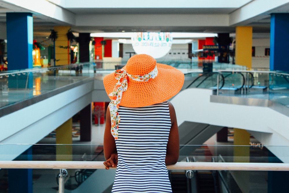 woman wearing orange summer hat inside mall