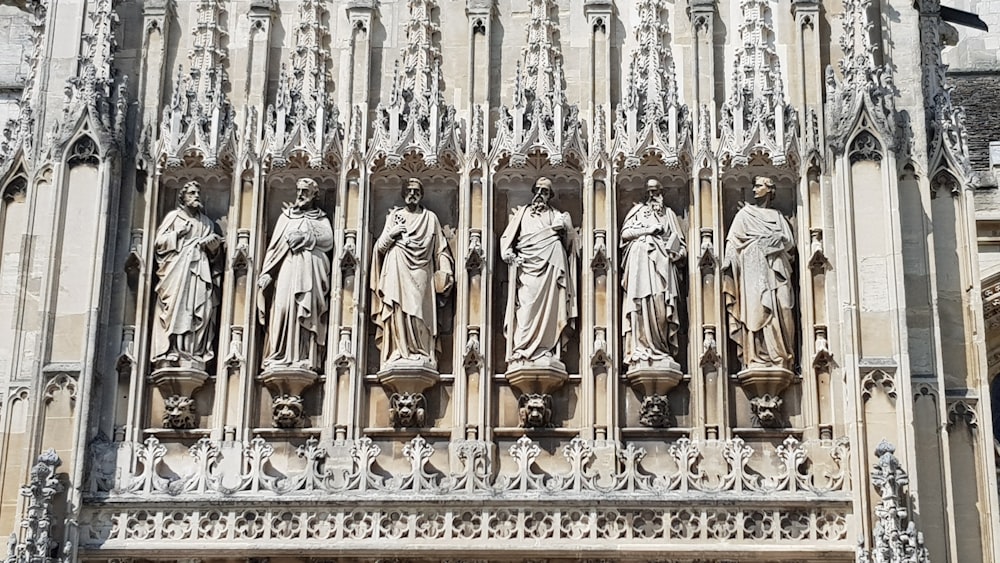 six statues of men on wall