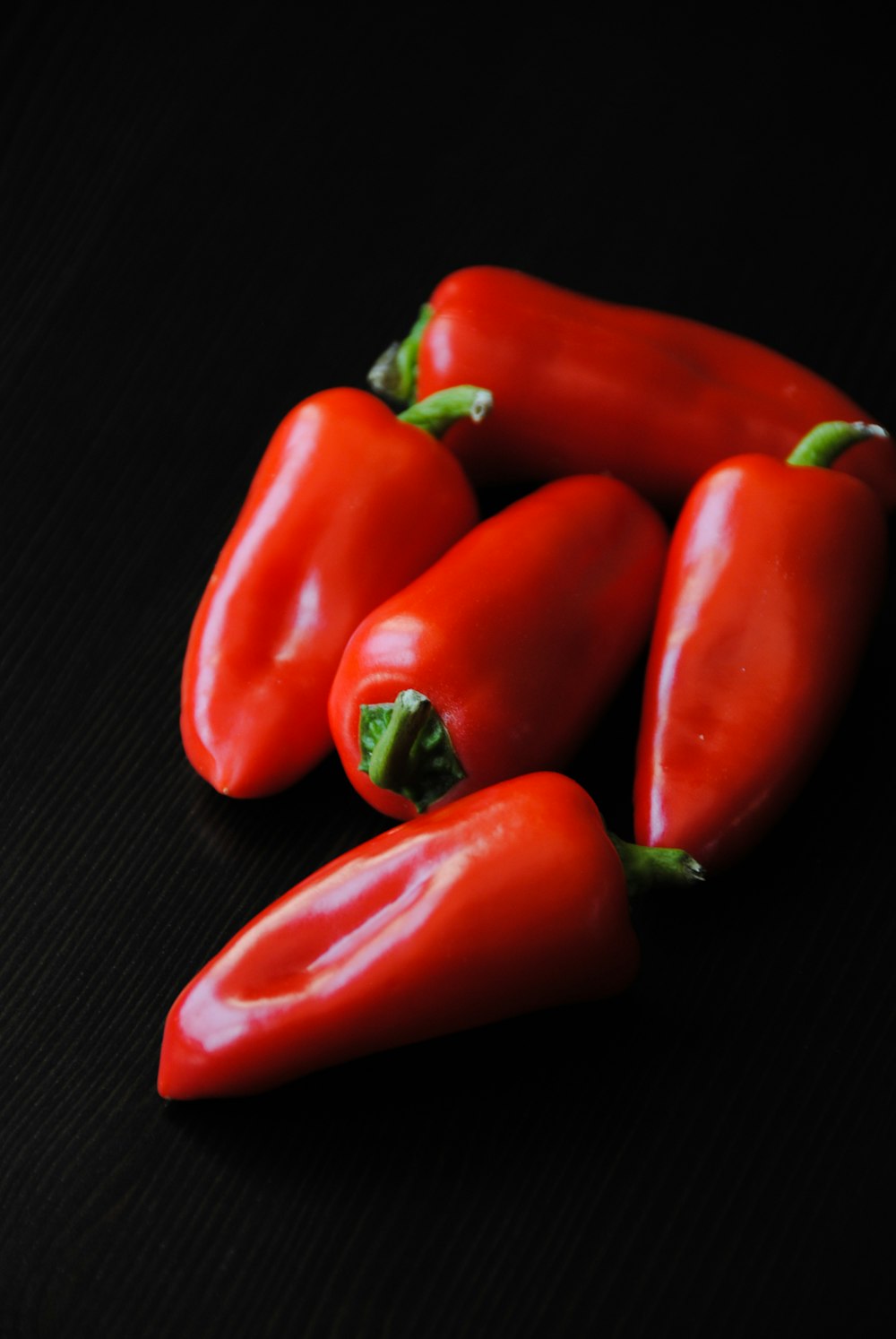 five red bell peppers on black textile