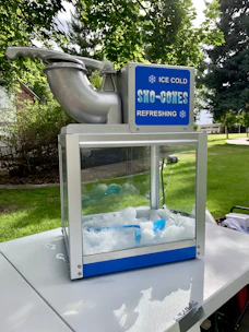 Snow cone machine with bright blue and red syrup bottles ready to serve icy treats.