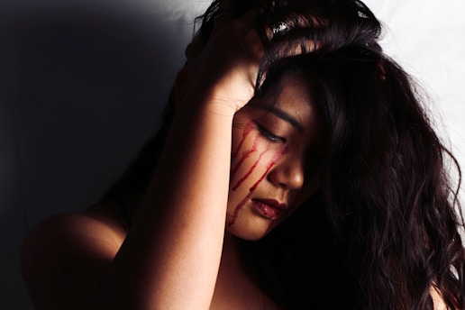 woman wearing red lipstick crying with blood on her face