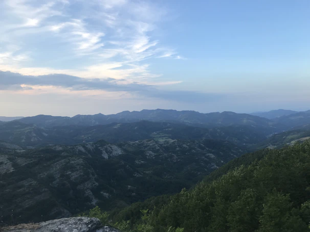 Wide panoramic view of a mountain range with sharp ridges and a soft teal gradient in the sky.
