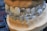 A close-up view of a dental model showcasing upper and lower sets of teeth with a transparent aligner placed between them. The model rests on a dark surface that appears to be part of a keyboard.