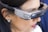 A person is wearing a pair of advanced augmented reality glasses with the label 'SVG by DTU' on the side, indicating a technological product. The glasses have a sleek, modern design and cover the eyes of the individual. The person has dark hair and is seen in a close-up view, focusing primarily on the device.