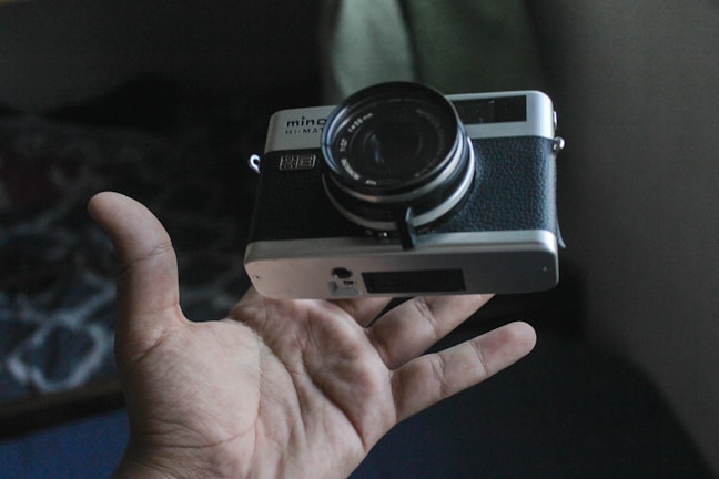 Hands holding a classic camera, highlighting its worn leather grip and metal details.