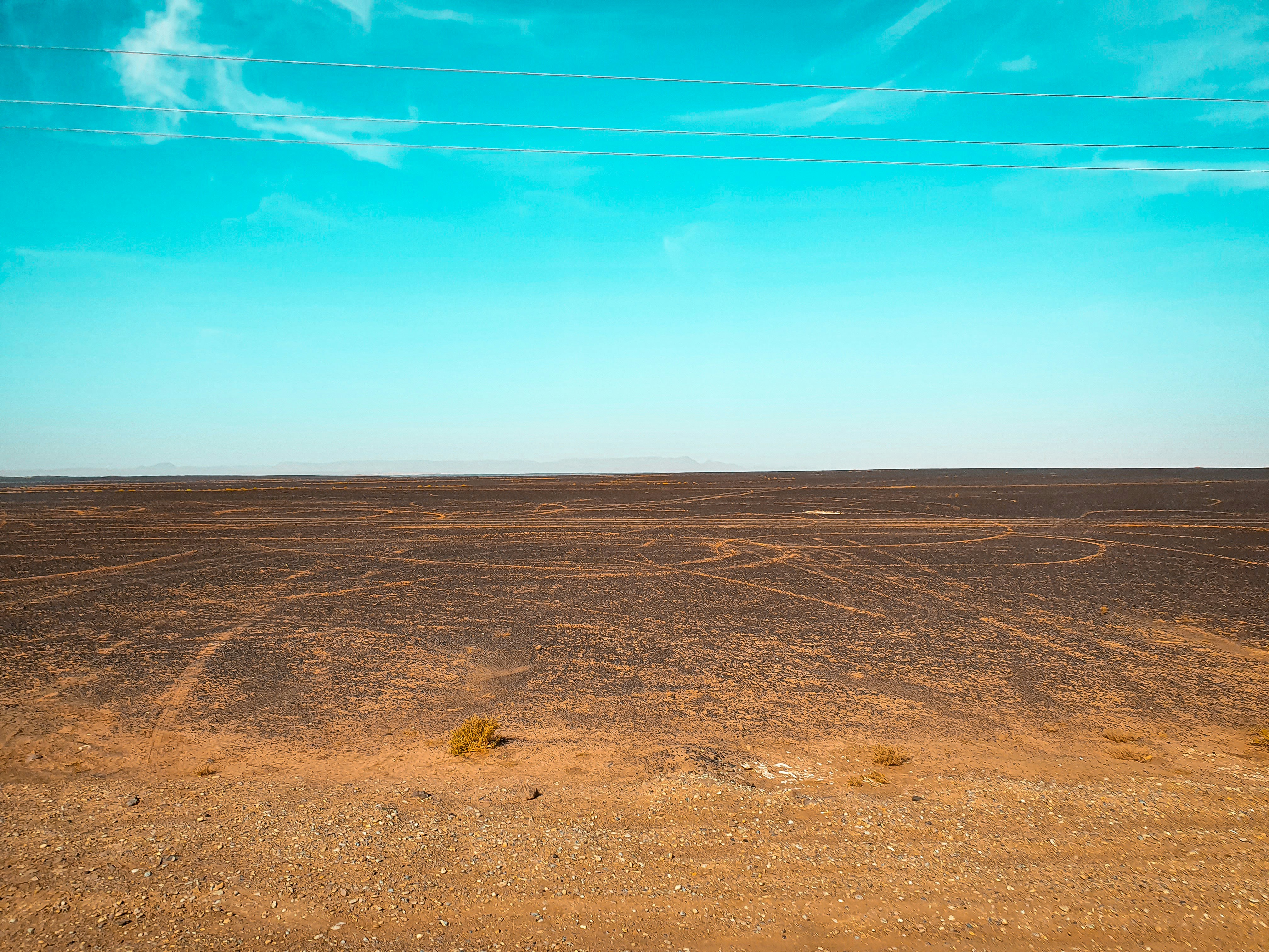 brown and black field under blue sky at daytime - Merzouga