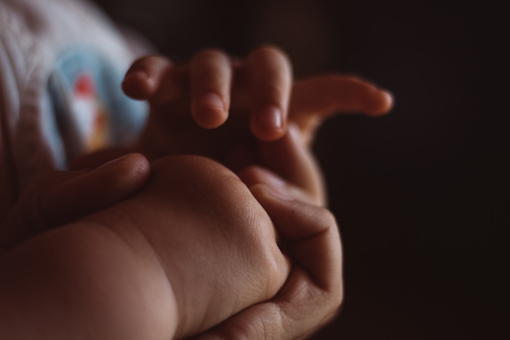 a close up of a person holding a baby's hand