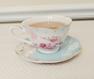 Elegant vintage teacup and saucer with herbal tea on a wooden table