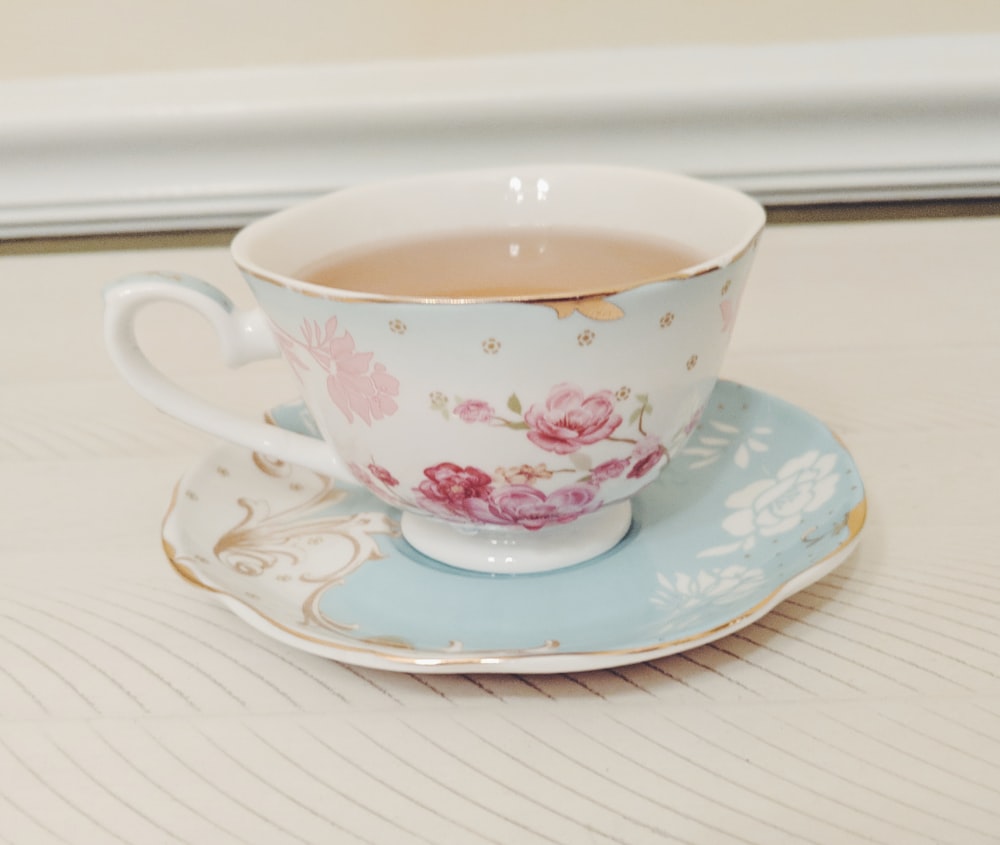 white and pink floral ceramic teacup with coffee