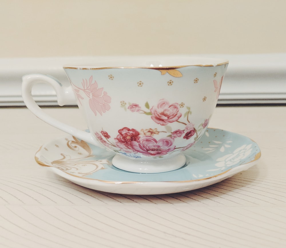 white and pink floral ceramic teacup and saucer