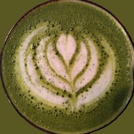 An overhead shot of a matcha latte with delicate latte art on top.