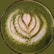 A vibrant matcha latte served in a clear glass with a sprinkle of matcha powder on top.