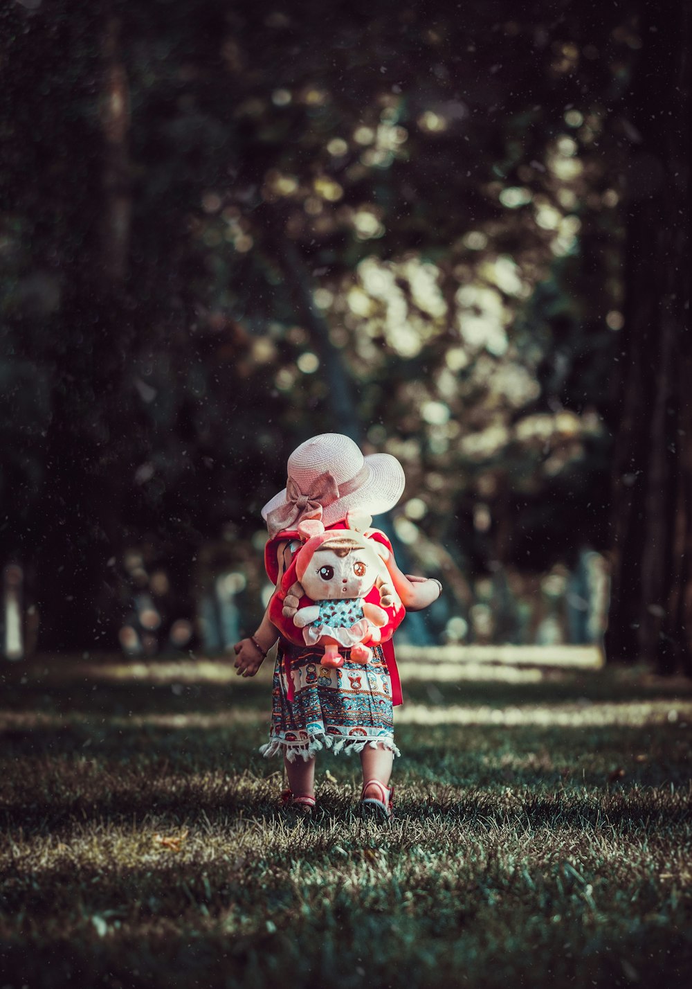 toddler wearing backpack walking near trees