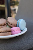 An assortment of colorful macarons arranged neatly on a white ceramic plate.