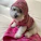 A small Chihuahua wearing a cozy pink hoodie with floral patterns, sitting happily on a colorful blanket.
