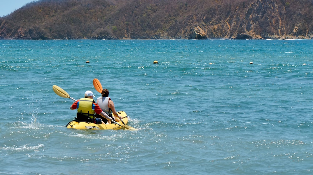 two person riding on yellow canoe on body of water during daytime