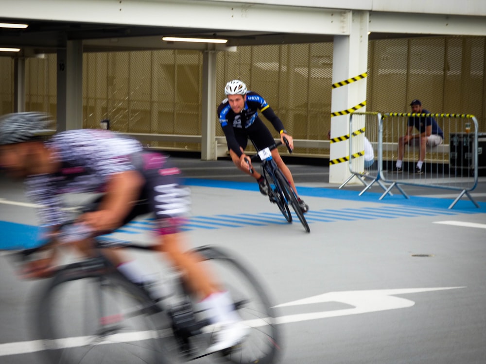 a man riding a bike down a street next to another man