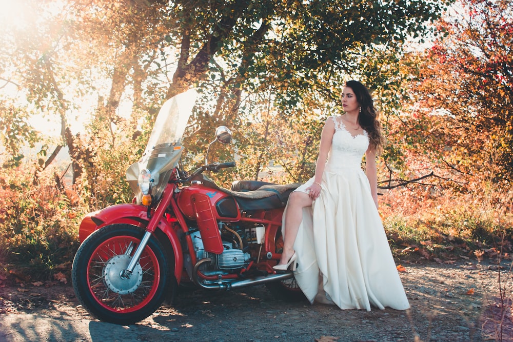 woman standing beside red touring motorcycle