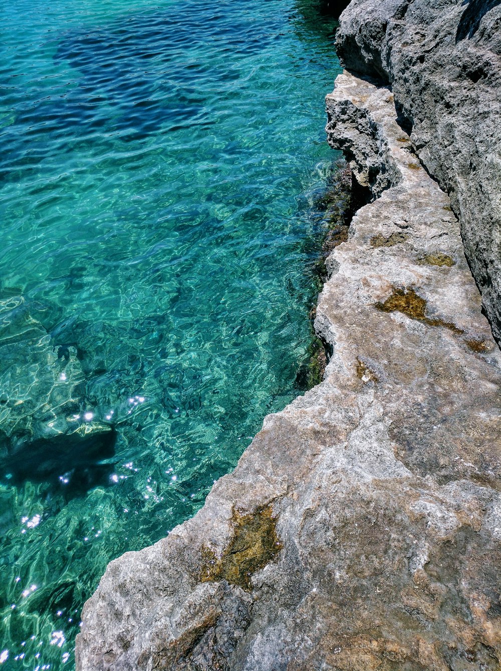 body of water beside gray rock