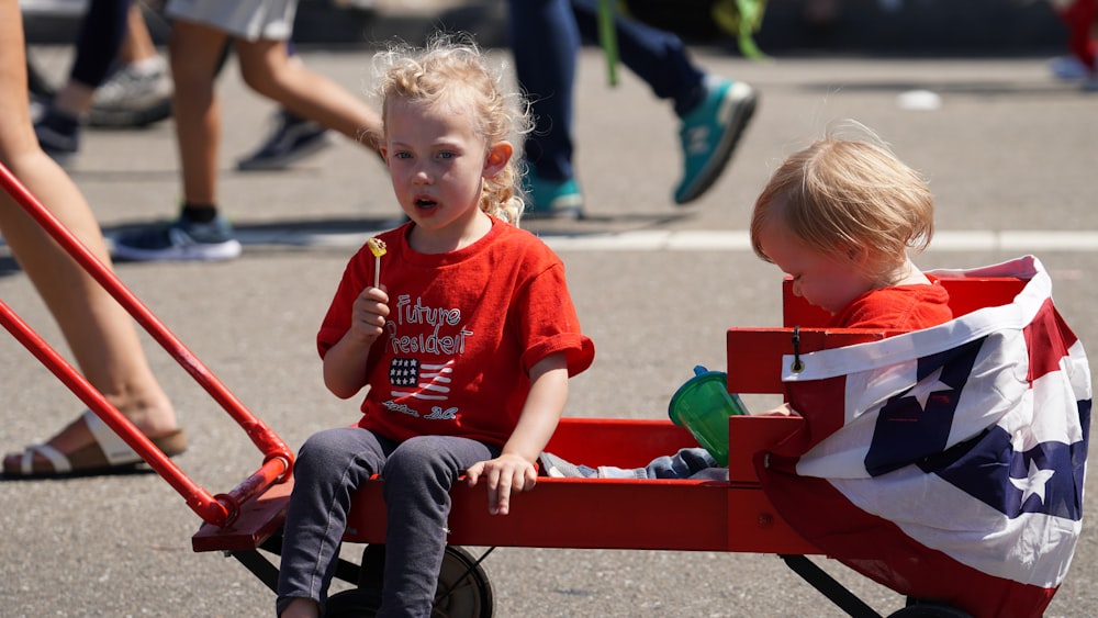 children sitting on red wagon