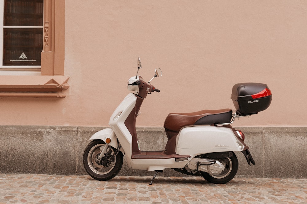 scooter de motor marrón y blanco cerca de la pared