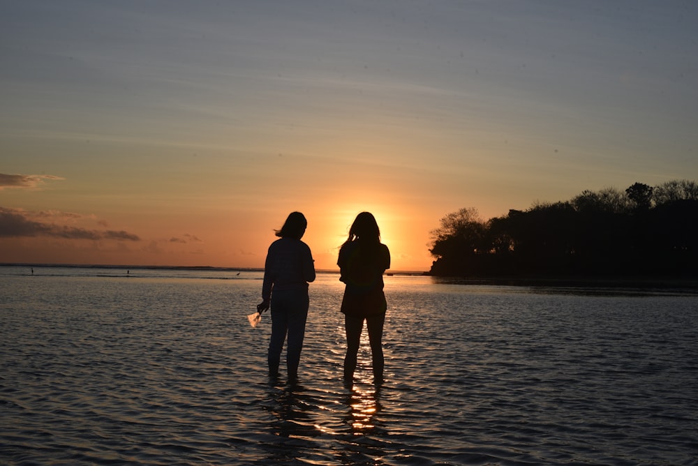 two women standing on the surface of water during daytime