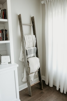 textiles hanging on gray wooden ladder