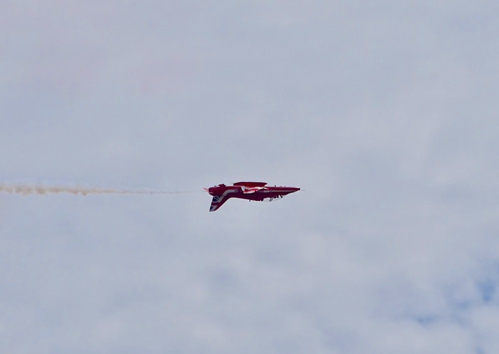 Rotes Flugzeug, das tagsüber unter bewölktem Himmel fliegt