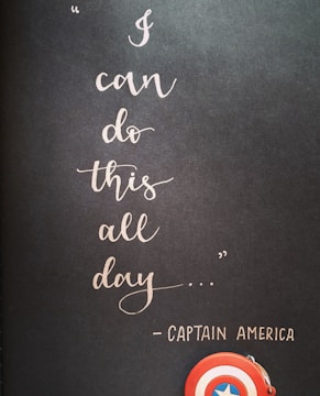 A motivational quote in elegant cursive handwriting on a dark background reads 'I can do this all day...' attributed to Captain America. Below the text, a small depiction of Captain America's shield is visible, emphasizing a theme of strength and perseverance.