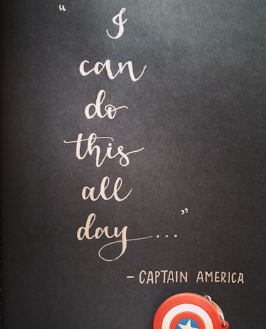 A motivational quote in elegant cursive handwriting on a dark background reads 'I can do this all day...' attributed to Captain America. Below the text, a small depiction of Captain America's shield is visible, emphasizing a theme of strength and perseverance.