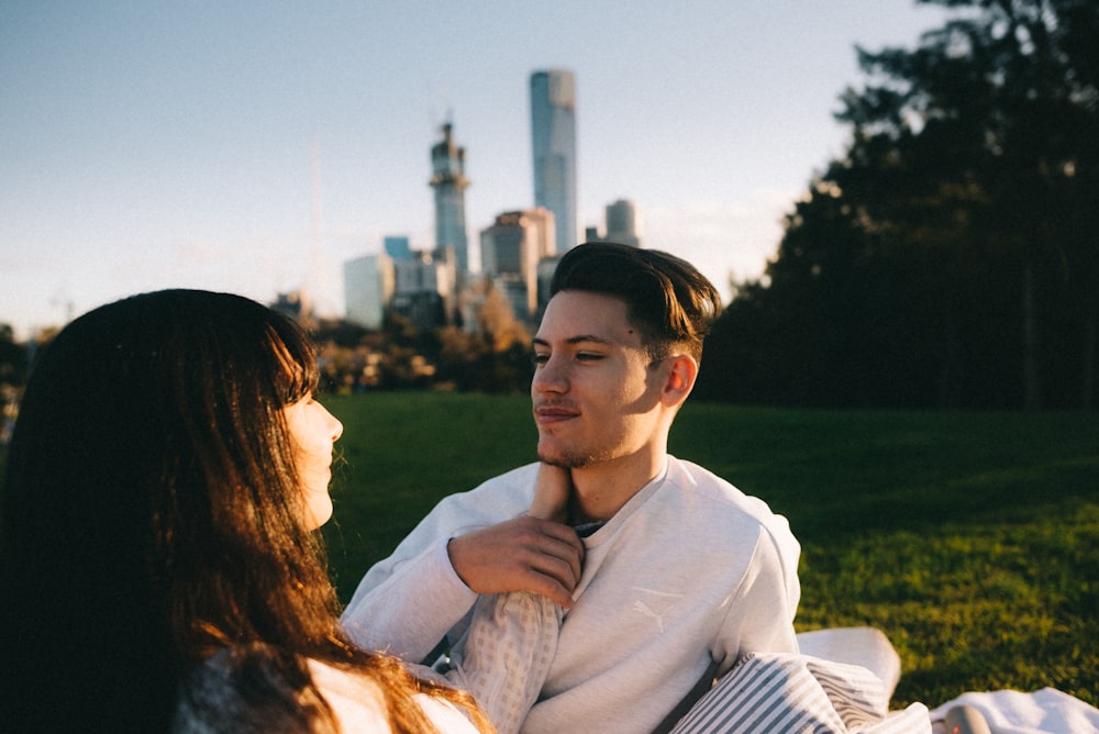 man and woman in white top sitting on green grass lawn