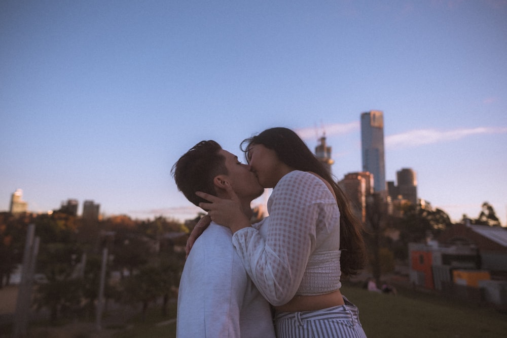 pareja besándose bajo el cielo azul durante el día