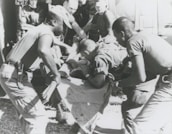 Paramedics assisting a patient on a stretcher outdoors.