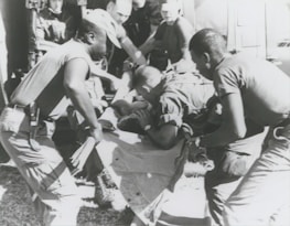 Paramedics assisting a patient on a stretcher outdoors.