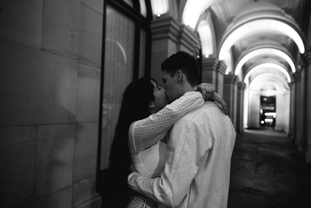 man kissing woman near wall