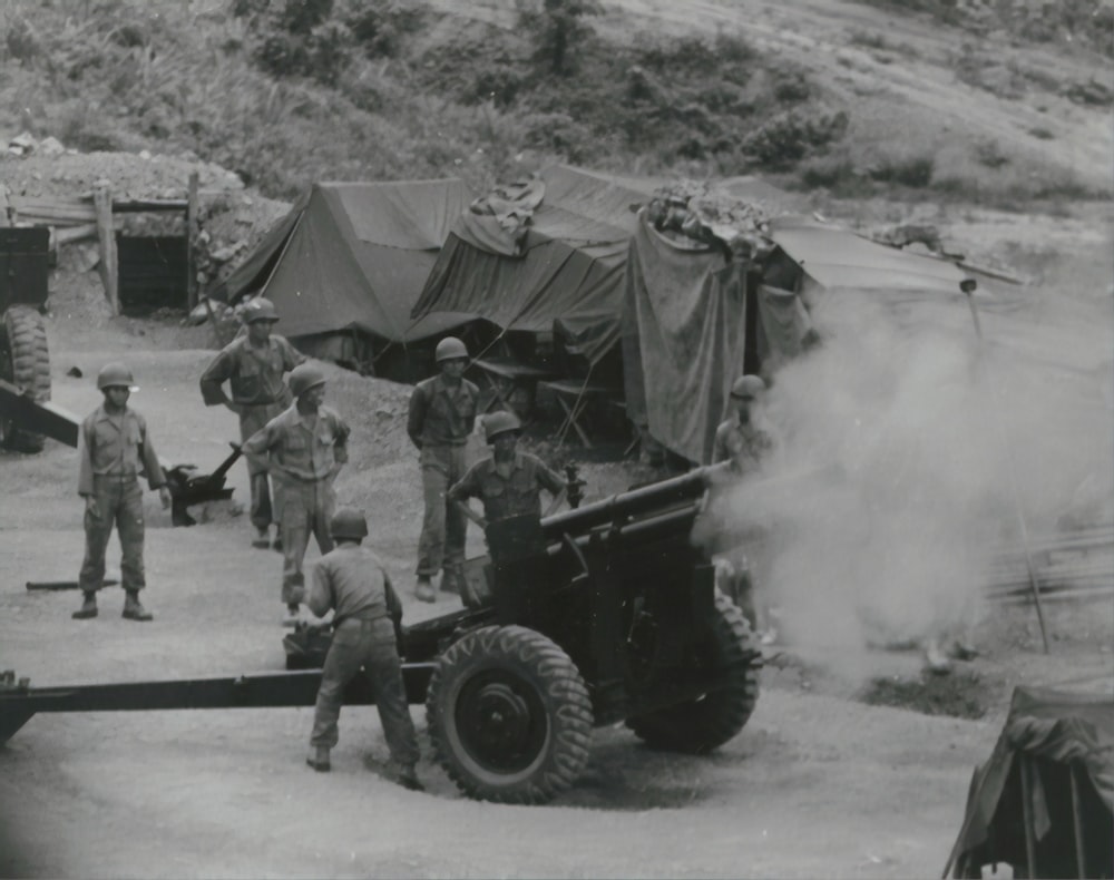 Foto en escala de grises de hombres parados cerca del cañón
