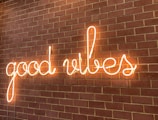Neon sign spelling out 'good vibes' mounted on a brick wall, creating a warm and inviting glow.