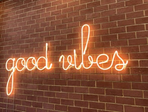 Neon sign spelling out 'good vibes' mounted on a brick wall, creating a warm and inviting glow.