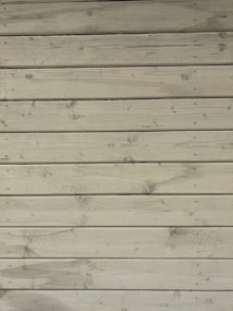 Weathered wooden planks arranged horizontally, showing natural knots and grains with a light, faded finish.