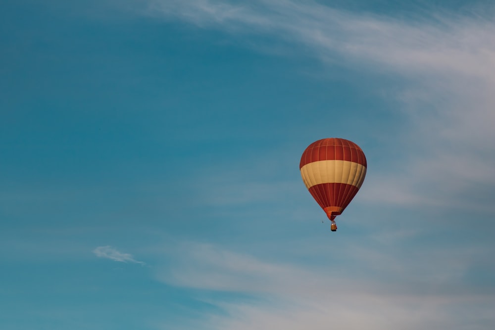 red and yellow hot air balloon flying across blue sky