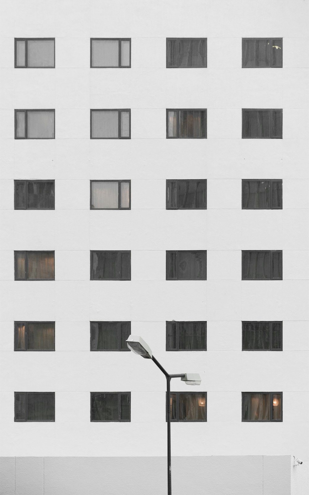 Lámpara de poste blanca y negra junto a edificio de hormigón blanco