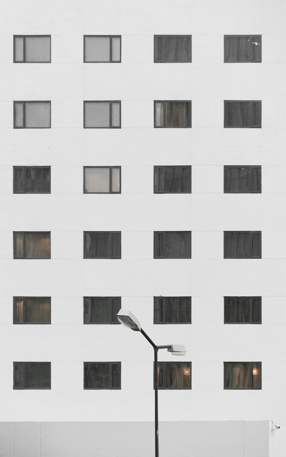 black and white post lamp beside white concrete building